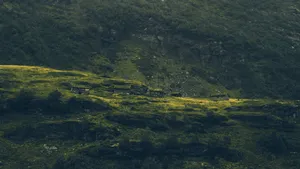 Berghang mit alten Holzhütten über einem Fjord